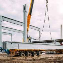 Installation process of prefabricated concrete beams on precast pillars. Industrial crane working